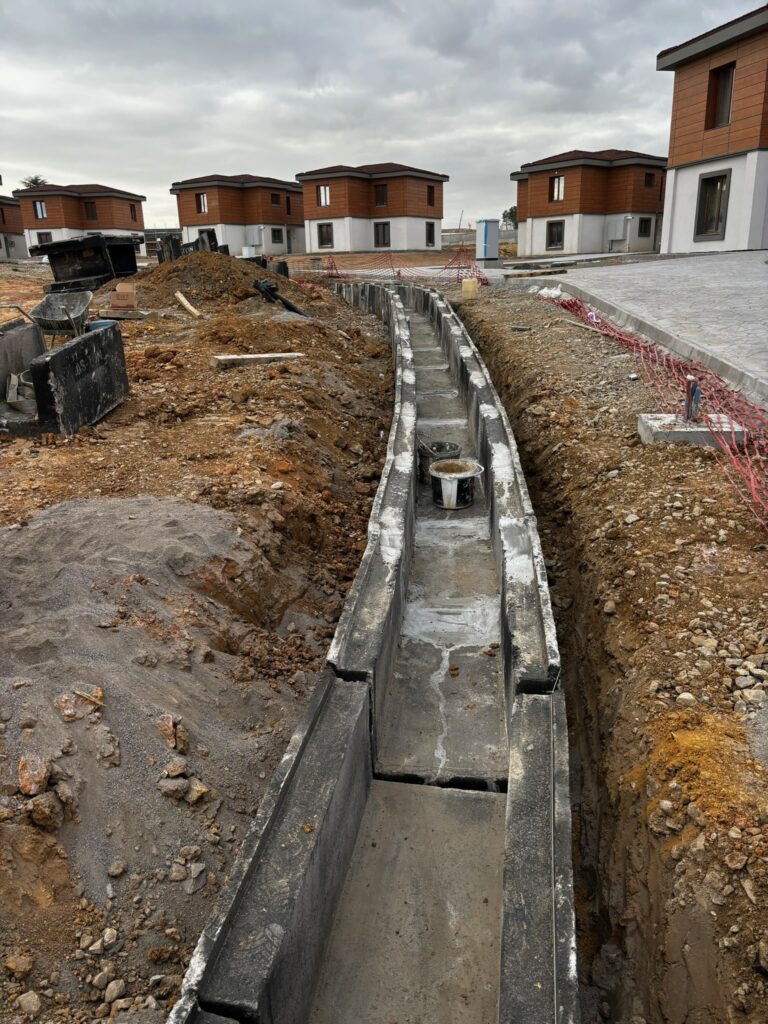 Profesyonel altyapı danışmanlığı kapsamında şantiyede geotekstil keçe ve mıcır filtre katmanlarıyla gerçekleştirilen delikli boru drenaj hattı imalatı.