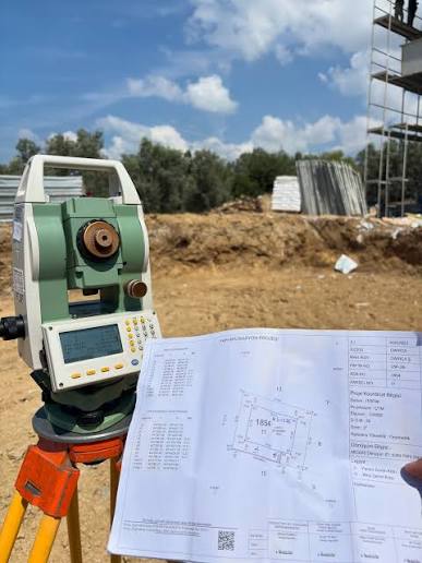 Şantiyede Total Station cihazı ve tablet ile topografik güzergâh ölçümü yapan harita mühendisi